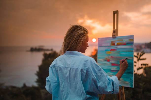 Woman painting at a Melanie's Canvas and Cocktails class