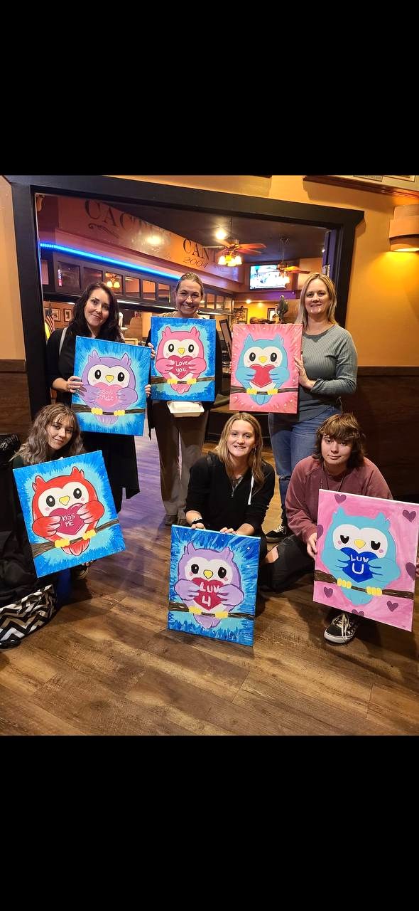 Group holding owl paintings at Cactus Cantina
