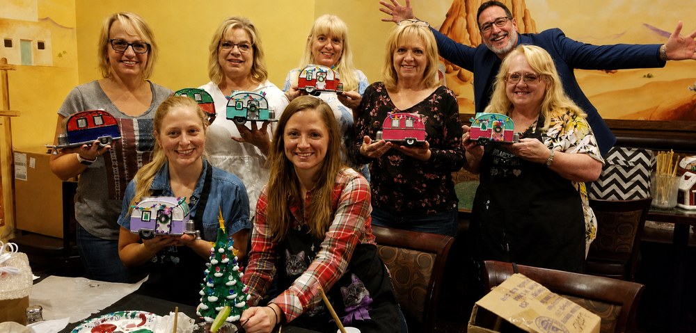Group of guests showing off their painted ceramic campers and trees